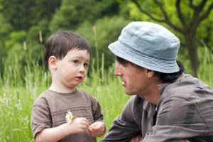 父亲和蹒跚学步的儿子在一个绿色的夏天的草地。